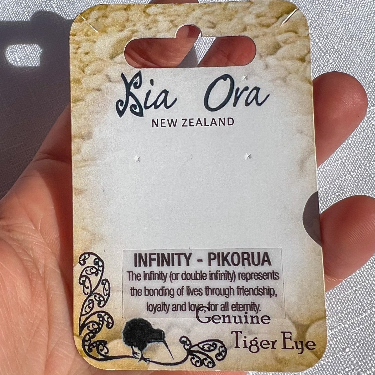 Card with 'Kia Ora New Zealand' branding and text about infinity and tiger eye on a textured background.