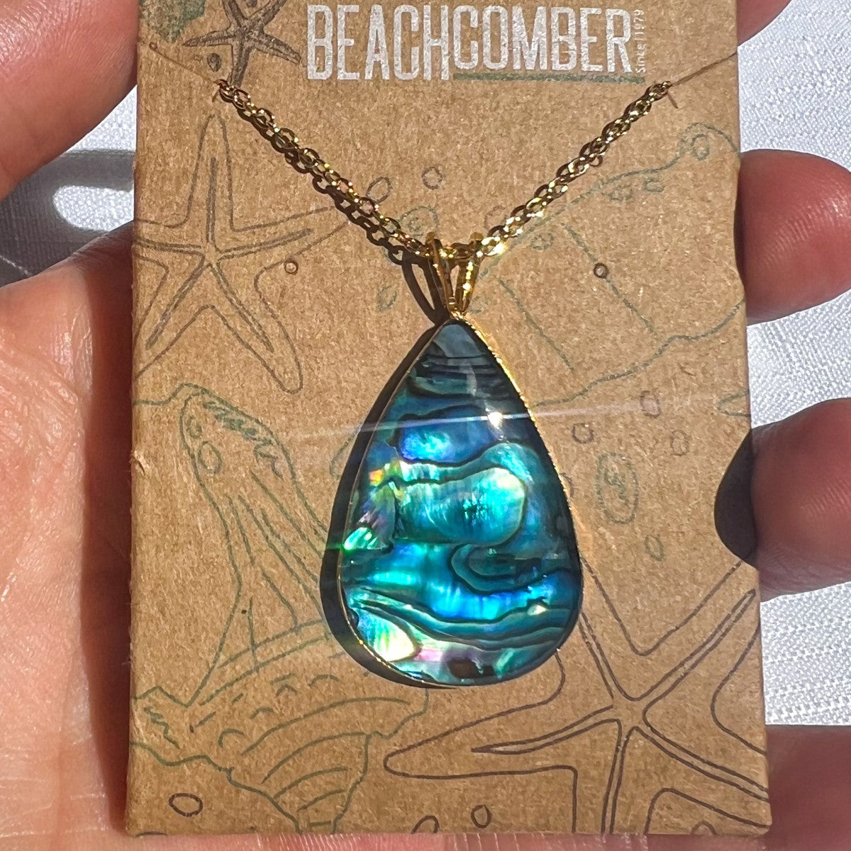 Necklace with a blue teardrop pendant on a 'Beachcomber' branded card.