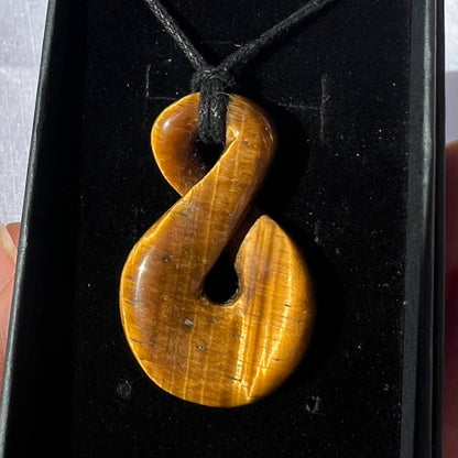 Brown hook-shaped pendant on a black background