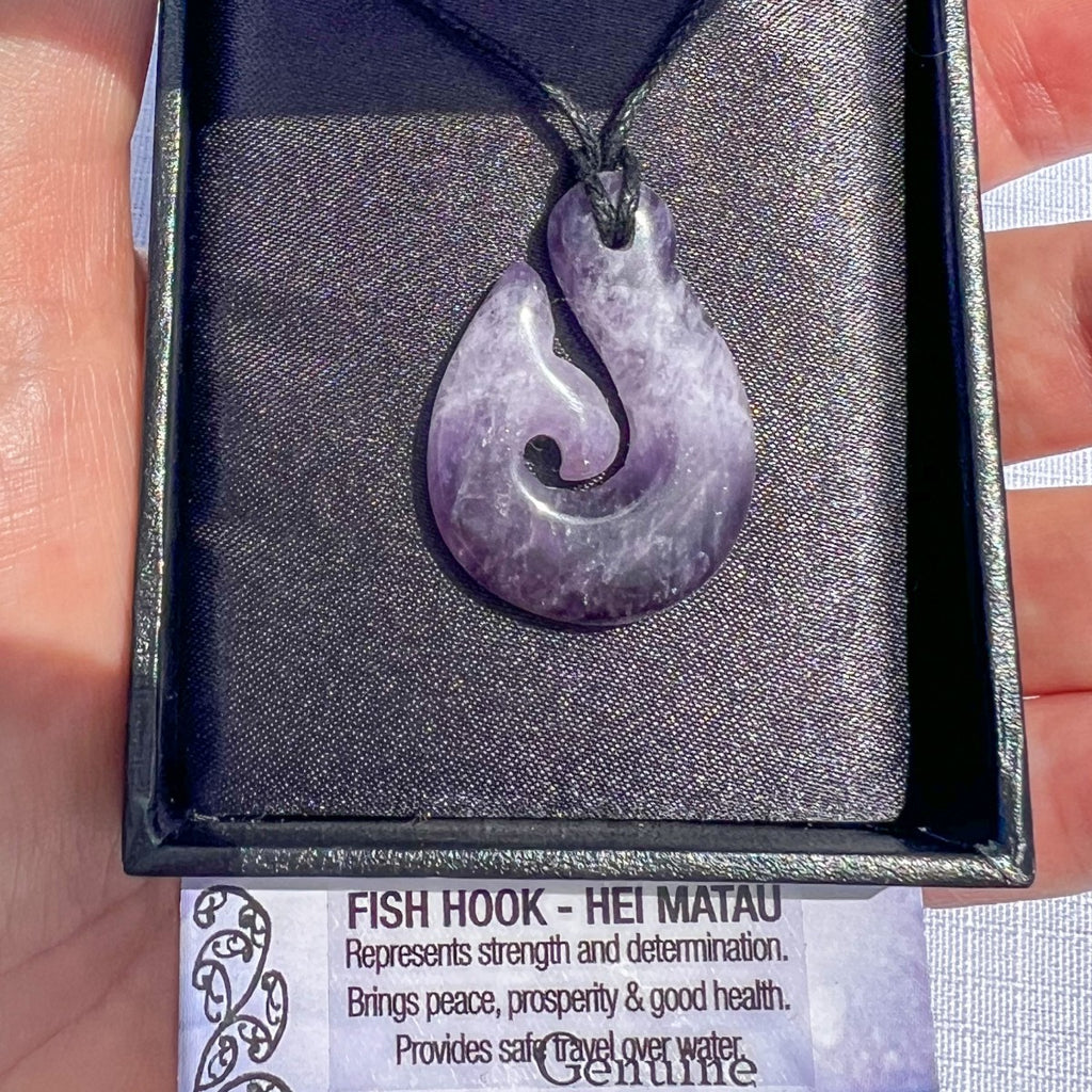 Amethyst Hei Matau (fish hook) pendant necklace on a black cord, symbolising strength, prosperity, and safe travel — hand-carved in New Zealand.