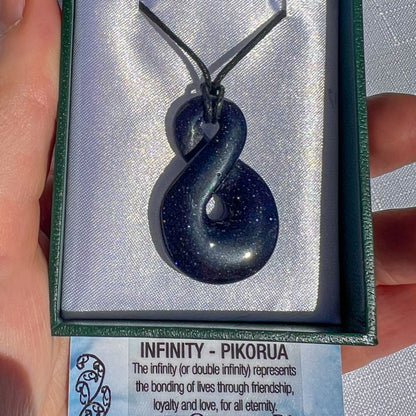 Blue pendant with 'Infinity - Pikorua' card held by a hand