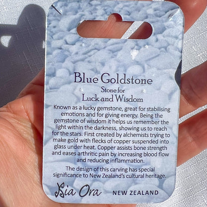 Blue Goldstone stone for luck and wisdom with descriptive card held by a hand