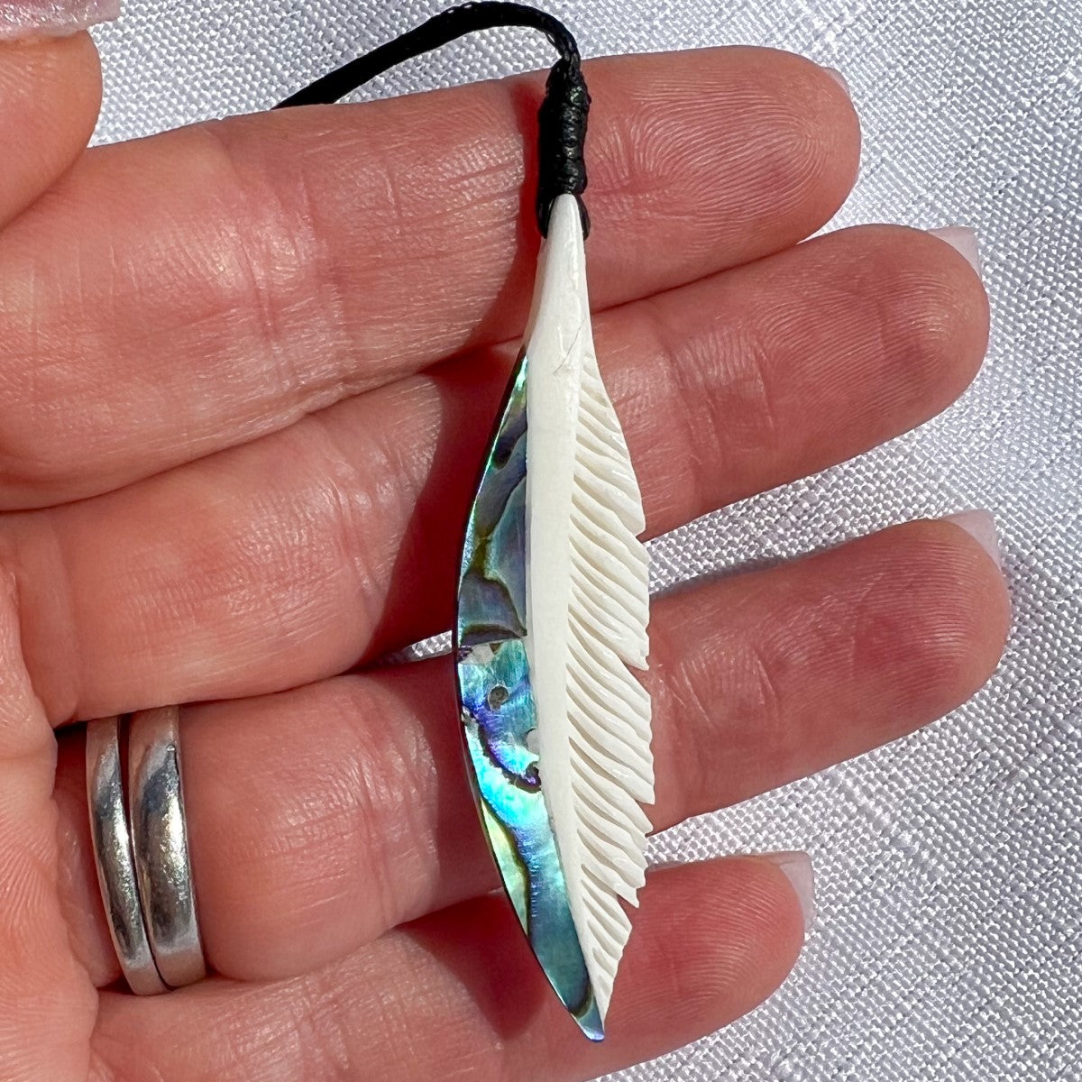 Hand-carved bone feather pendant 55mm with paua shell inlay – traditional Māori design symbolising trust, honour, and respect. Adjustable cord. Ships fast from Australia. Free shipping over $100.