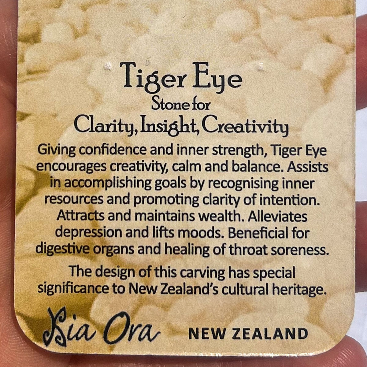 Close-up of a Tiger Eye meaning card from Aotearoa New Zealand, describing the stone as one for clarity, insight, and creativity, promoting confidence, balance, and inner strength.