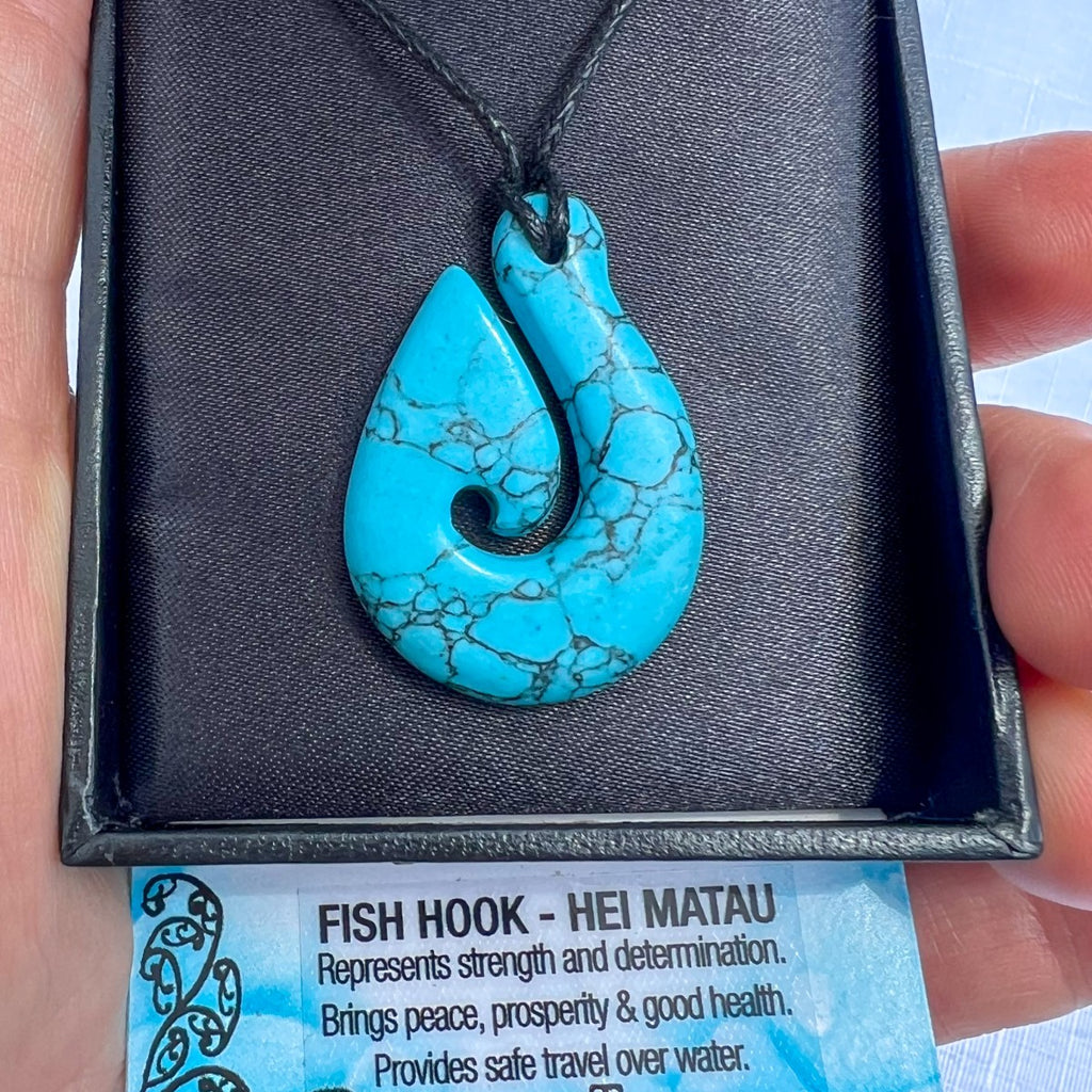 Turquoise Howlite Hei Matau (fish hook) pendant necklace on a black cord, symbolising strength, friendship, and protection — hand-carved in New Zealand.