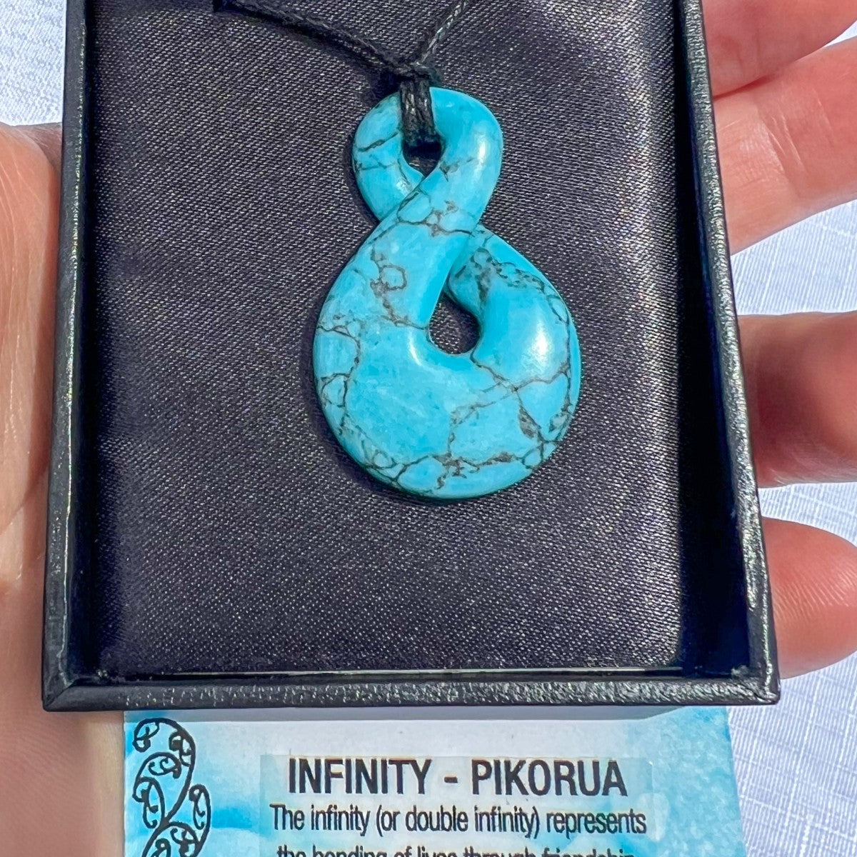 Turquoise Howlite Pikorua (infinity twist) pendant necklace on a black cord, symbolising friendship, love, and eternal connection — hand-carved in New Zealand.